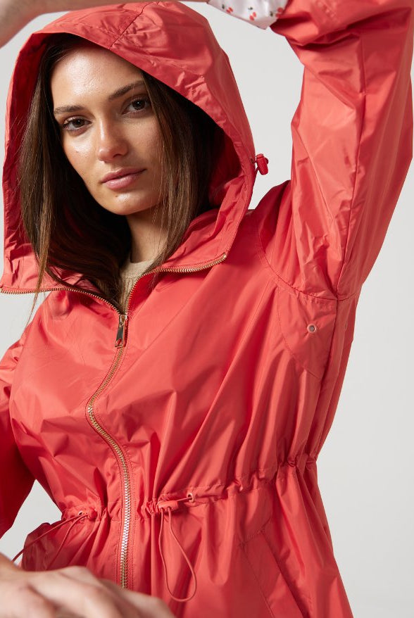 The Coral Spritz raincoat in coral red, lightweight hooded waterproof raincoat ideal for South Africa’s rainy season and wet climate