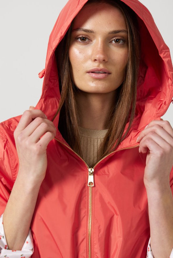 The Coral Spritz raincoat in coral red, lightweight hooded waterproof raincoat ideal for South Africa’s rainy season and wet climate