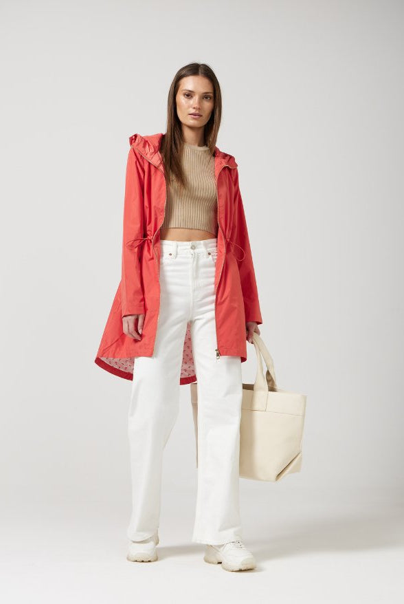 The Coral Spritz raincoat in coral red, lightweight hooded waterproof raincoat ideal for South Africa’s rainy season and wet climate