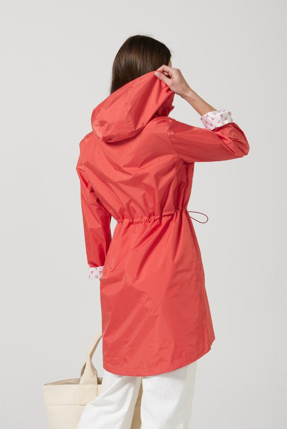 The Coral Spritz raincoat in coral red, lightweight hooded waterproof raincoat ideal for South Africa’s rainy season and wet climate