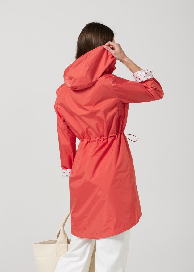 The Coral Spritz raincoat in coral red, lightweight hooded waterproof raincoat ideal for South Africa’s rainy season and wet climate